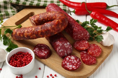 Photo of Different smoked sausages and spices on white wooden table, closeup