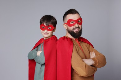 Photo of Father and his son wearing superhero costumes on gray background