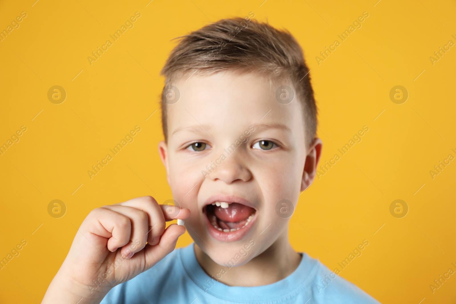 Photo of Cute little boy with missing tooth on orange background. Waiting for tooth fairy