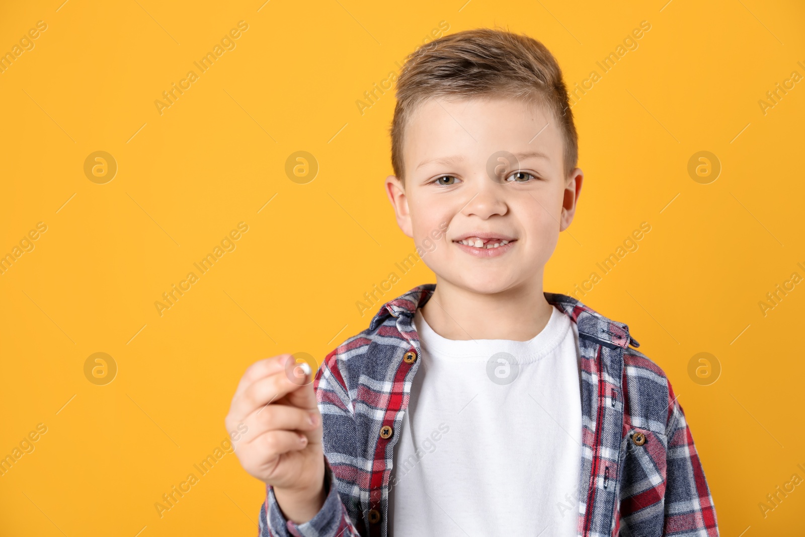 Photo of Cute little boy with missing tooth on orange background, space for text. Waiting for tooth fairy