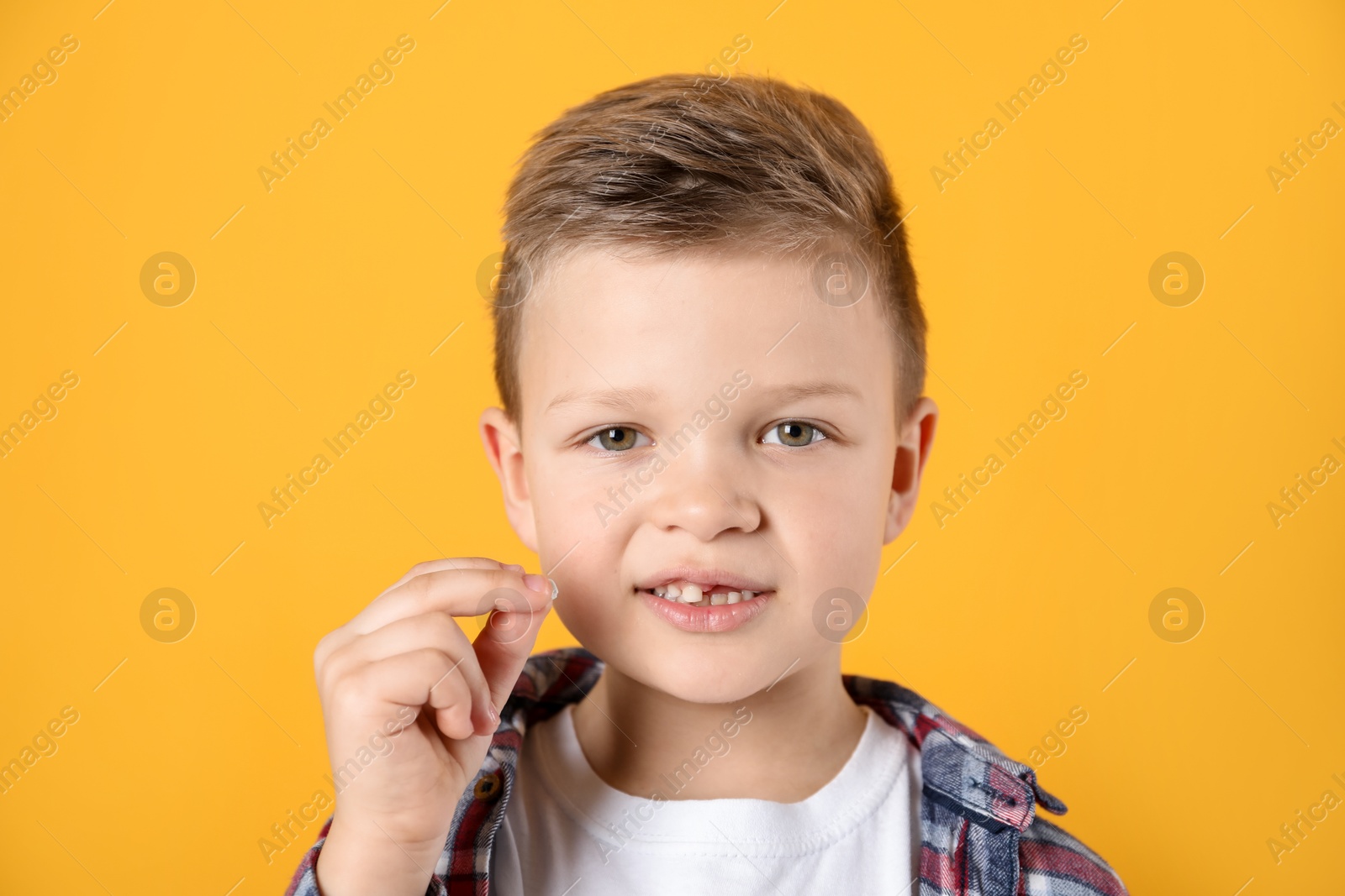 Photo of Cute little boy with missing tooth on orange background. Waiting for tooth fairy