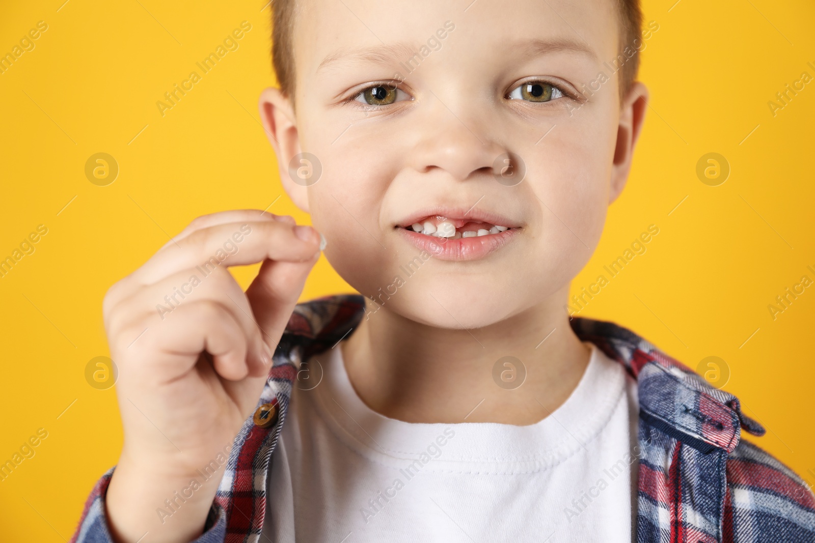 Photo of Cute little boy with missing tooth on orange background, closeup. Waiting for tooth fairy