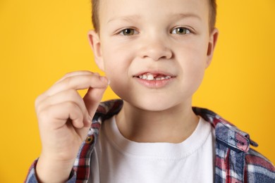 Photo of Cute little boy with missing tooth on orange background, closeup. Waiting for tooth fairy