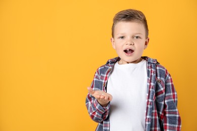 Photo of Cute little boy with missing tooth on orange background, space for text. Waiting for tooth fairy