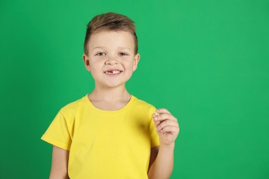 Photo of Cute little boy with missing tooth on green background, space for text. Waiting for tooth fairy