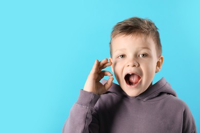 Cute little boy with missing tooth on light blue background, space for text. Waiting for tooth fairy