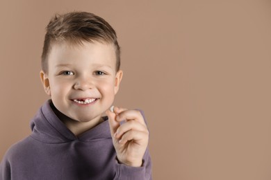 Photo of Cute little boy with missing tooth on dark beige background, space for text. Waiting for tooth fairy