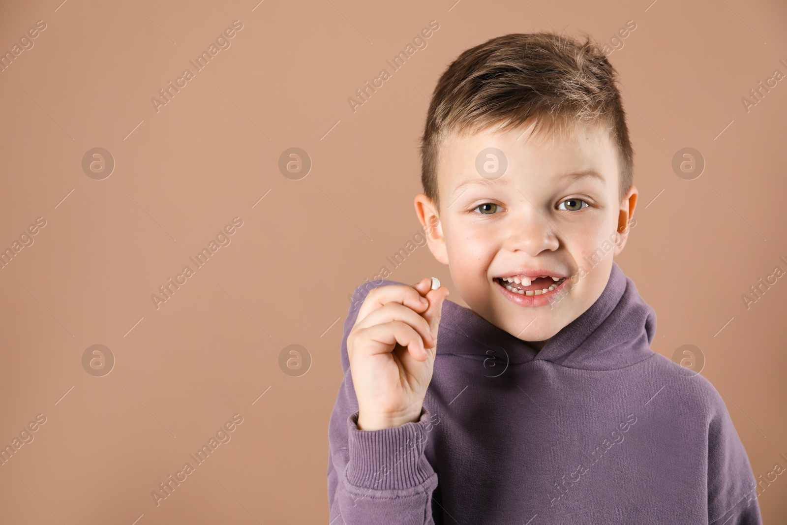 Photo of Cute little boy with missing tooth on dark beige background, space for text. Waiting for tooth fairy