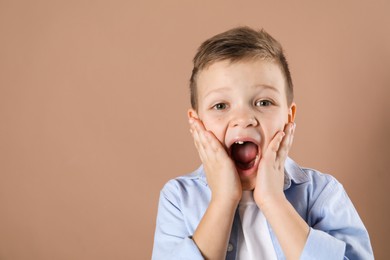 Photo of Cute little boy with missing tooth on dark beige background, space for text