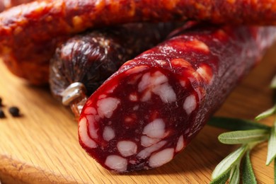 Photo of Different smoked sausages and rosemary on wooden board, closeup