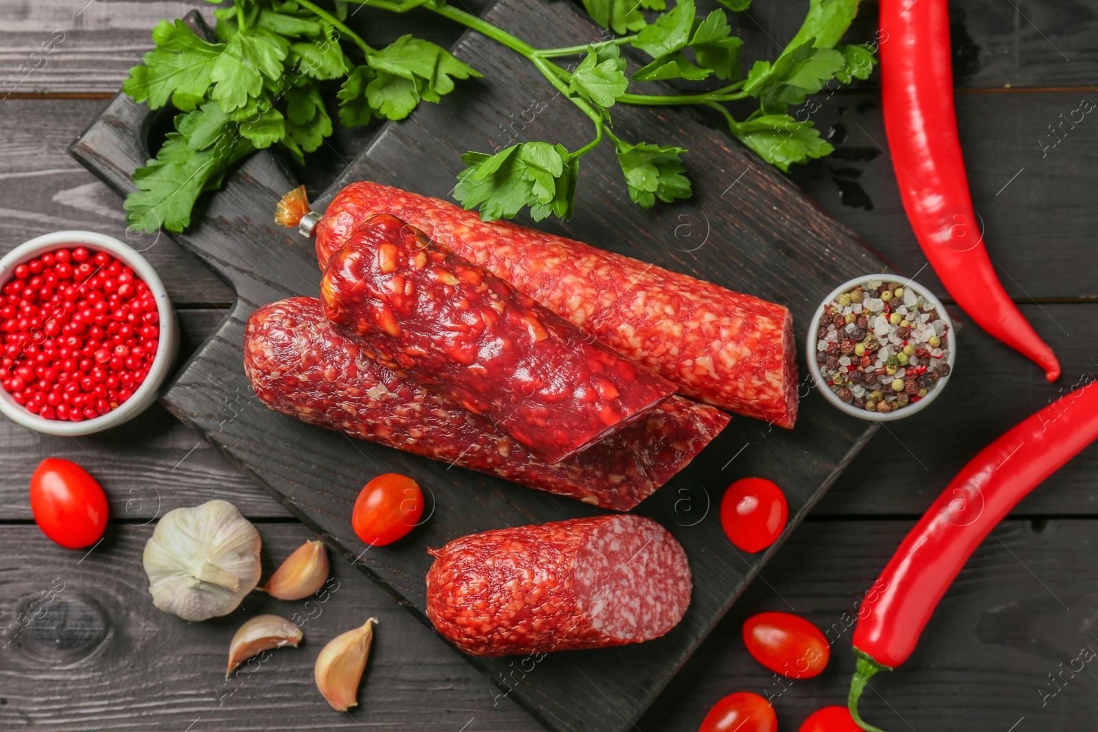 Photo of Different smoked sausages and products on black wooden table, flat lay