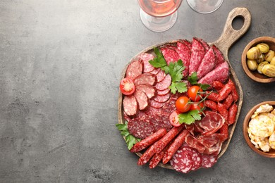 Photo of Different smoked sausages slices served on grey table, flat lay. Space for text