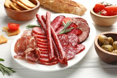 Photo of Different smoked sausages slices served on white wooden table, closeup