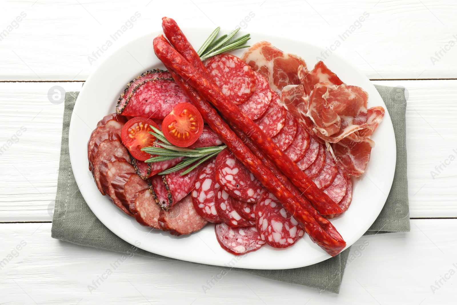 Photo of Different smoked sausages slices served on white wooden table, top view