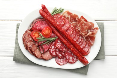 Photo of Different smoked sausages slices served on white wooden table, top view