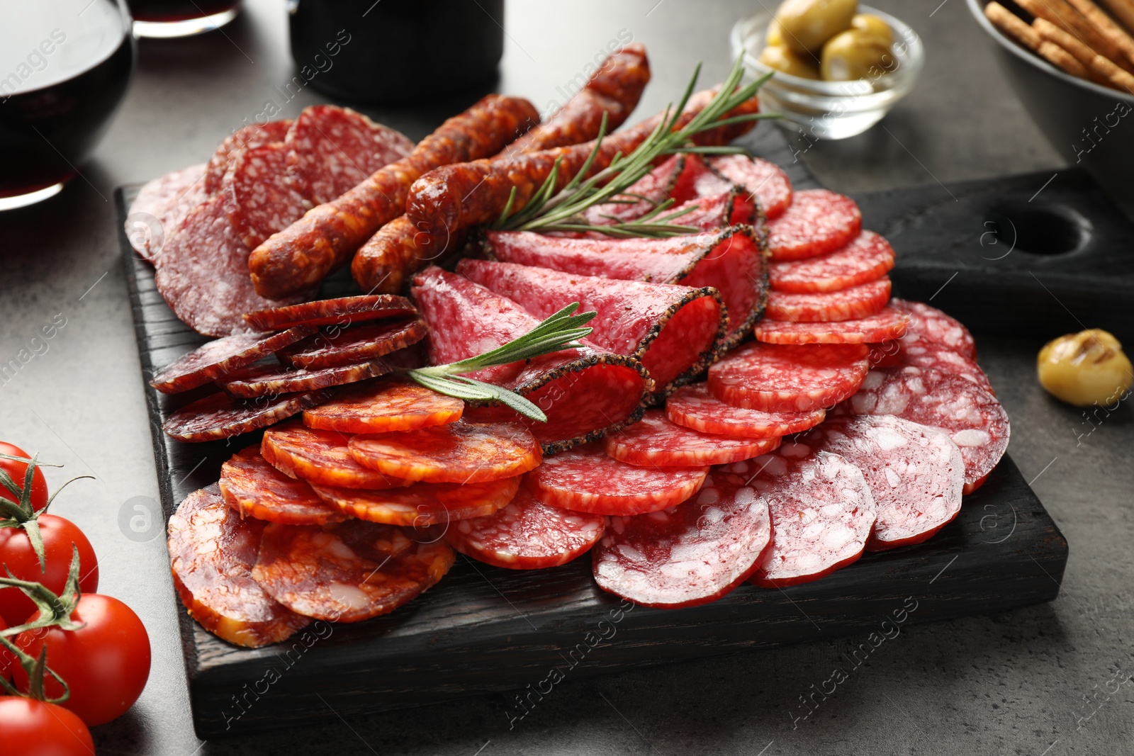 Photo of Different smoked sausages slices served on grey table, closeup