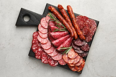 Photo of Different smoked sausages slices served on light table, top view