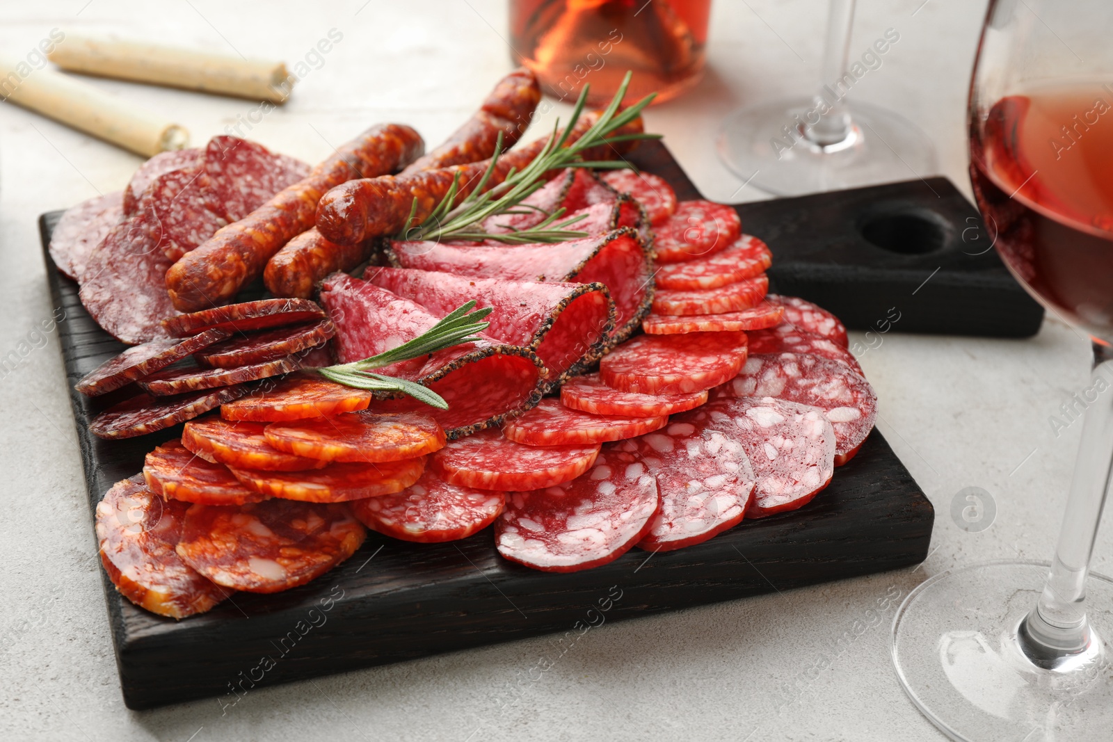 Photo of Different smoked sausages slices served on light table, closeup