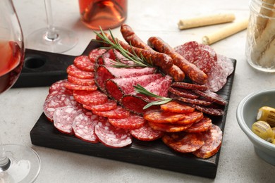 Photo of Different smoked sausages slices served on light table, closeup