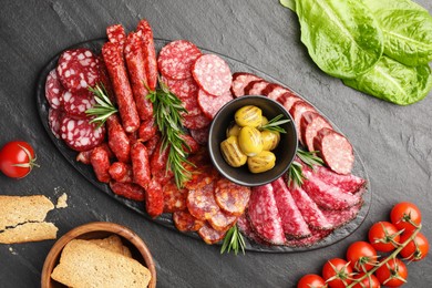 Photo of Different smoked sausages and other snacks on black table, flat lay