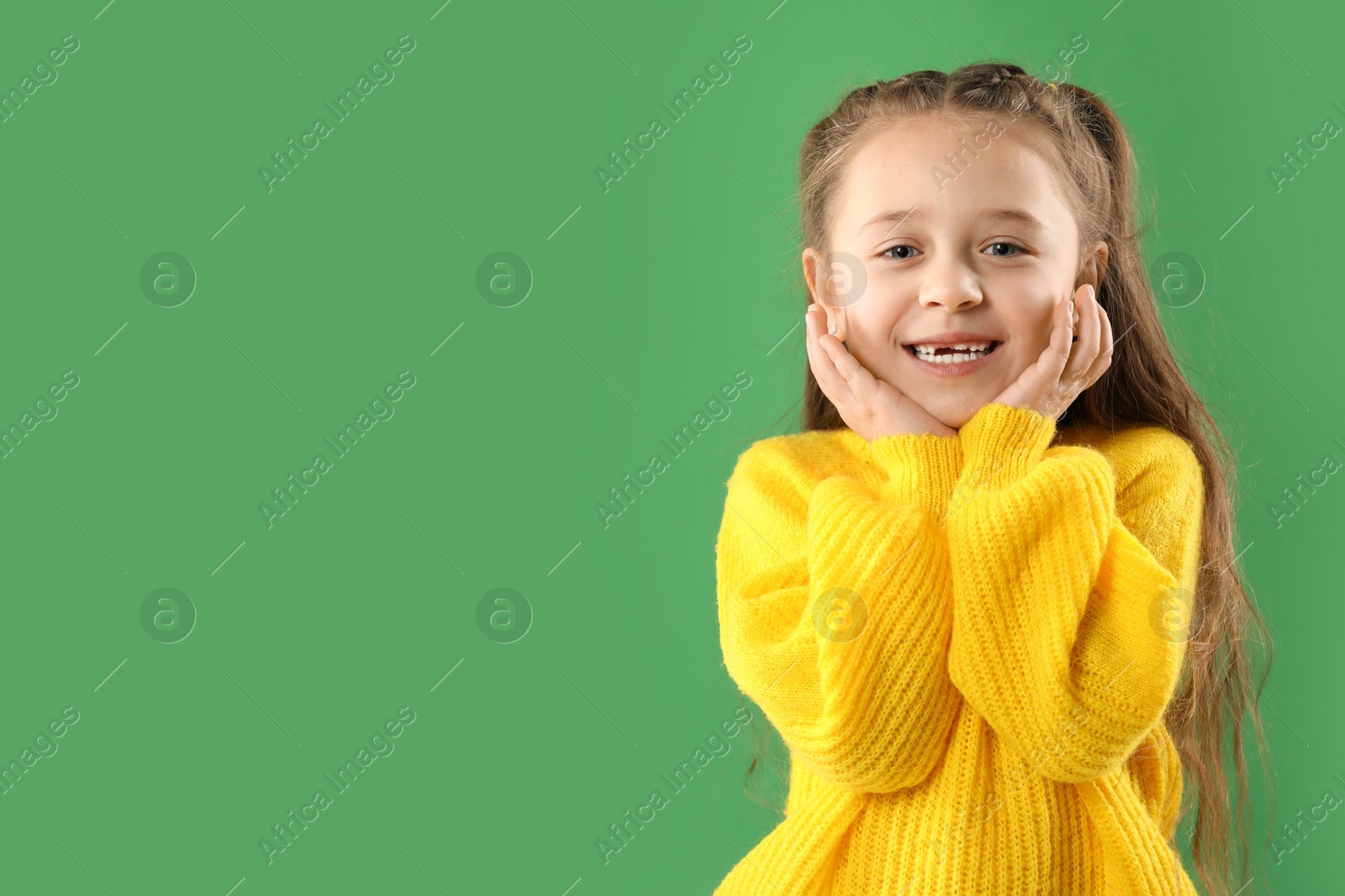 Photo of Portrait of cute little girl with missing tooth on green background, space for text