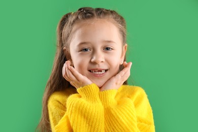 Photo of Portrait of cute little girl with missing tooth on green background