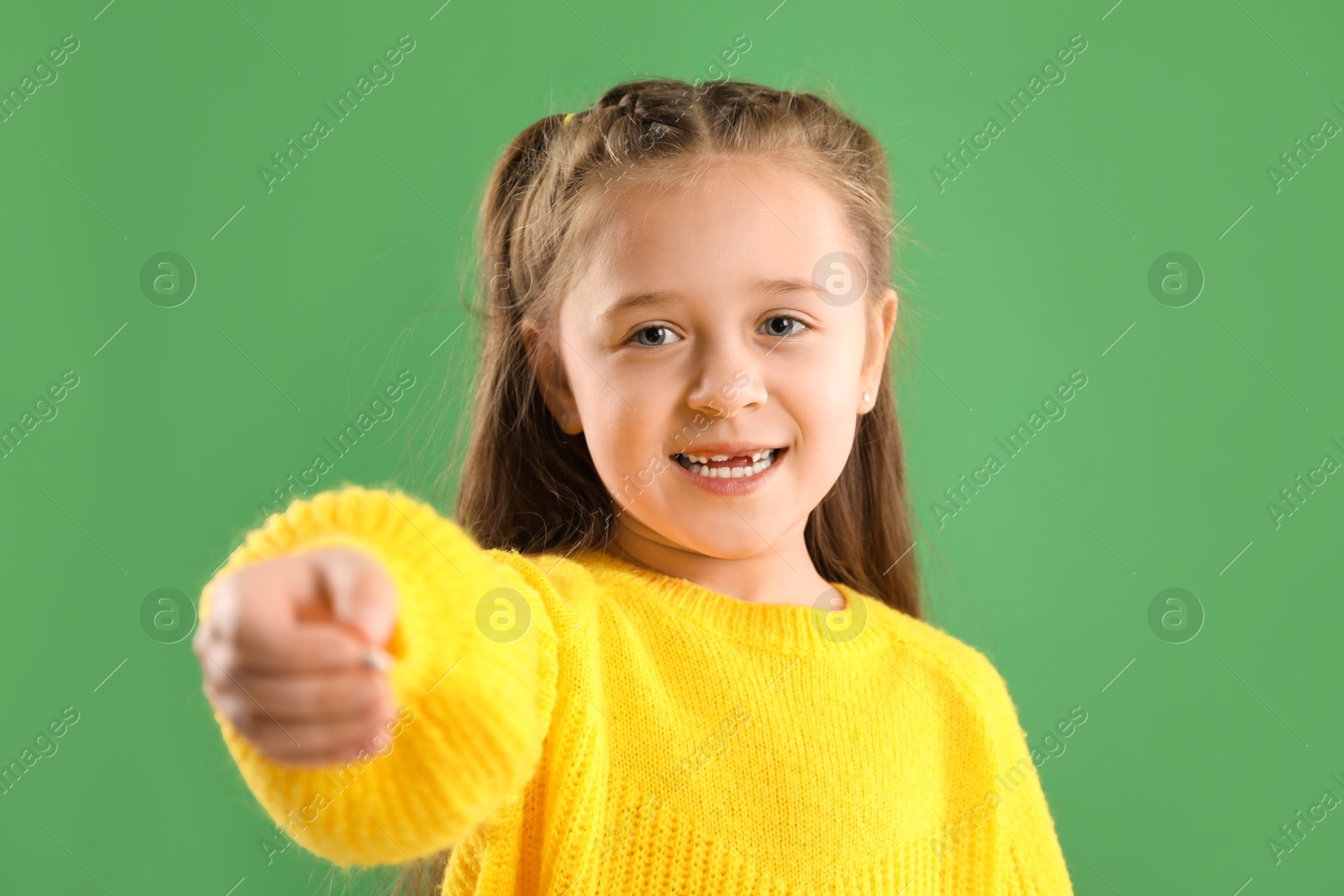 Photo of Cute little girl with missing tooth on green background. Waiting for tooth fairy