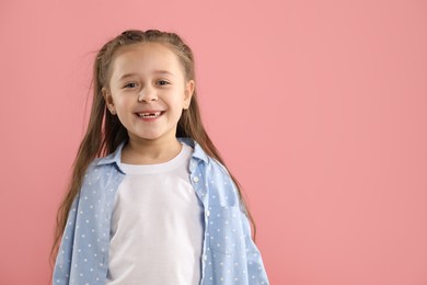 Photo of Portrait of cute little girl with missing tooth on pink background, space for text