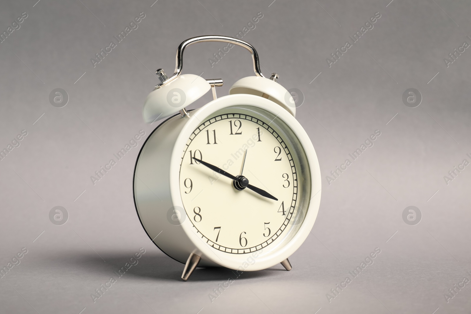 Photo of One white alarm clock on grey background