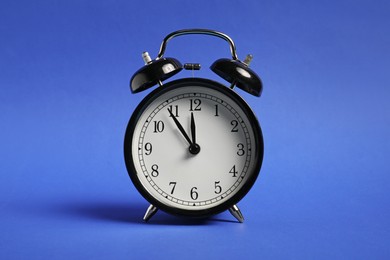 Photo of One black alarm clock on blue background