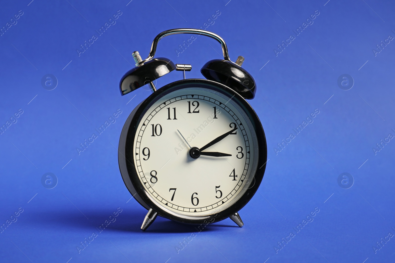 Photo of One black alarm clock on blue background