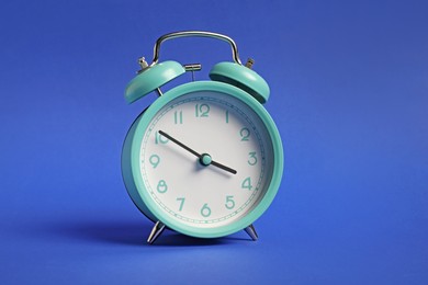 Photo of One turquoise alarm clock on blue background