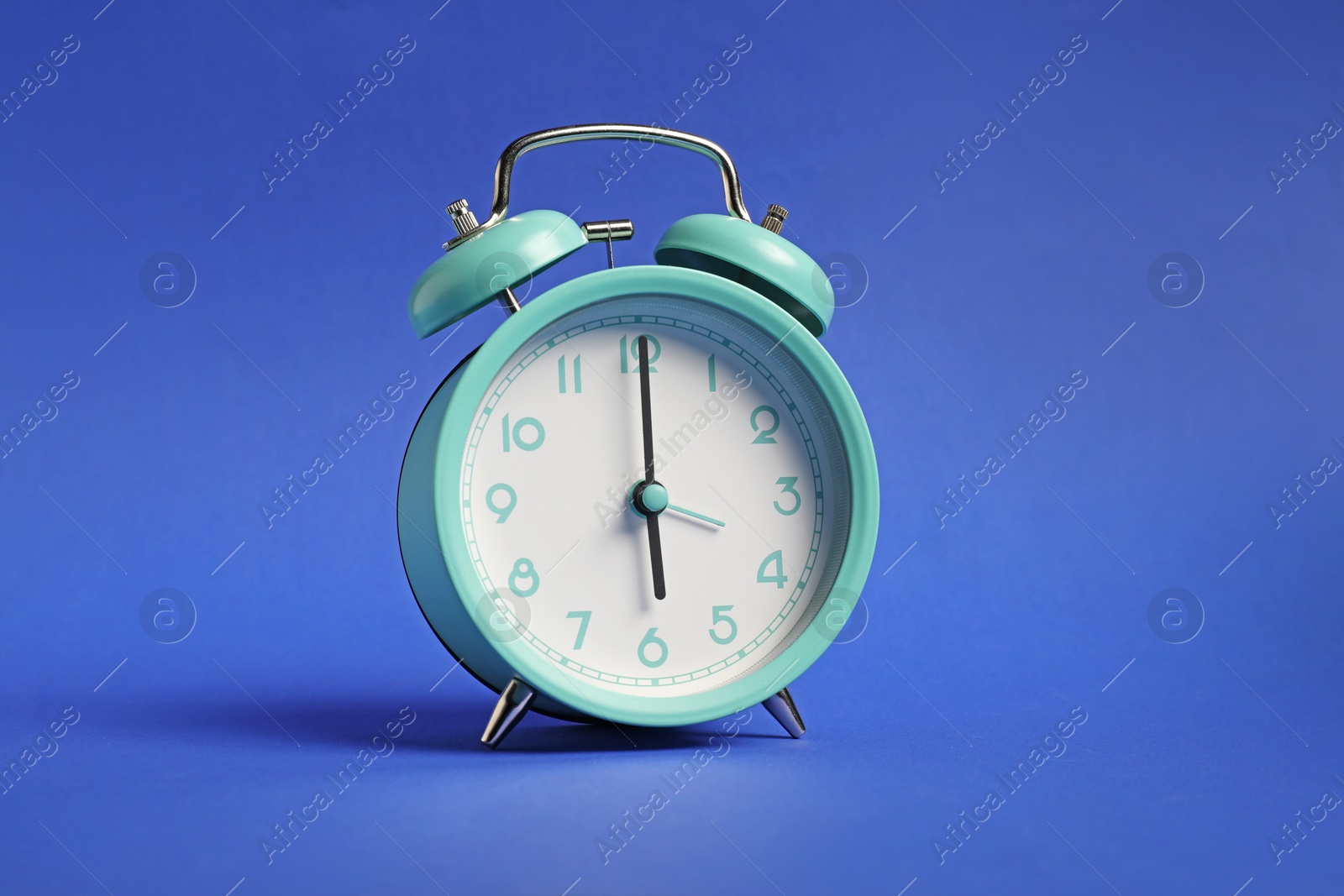 Photo of One turquoise alarm clock on blue background