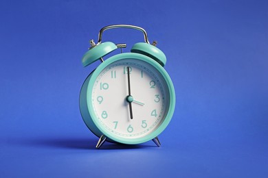 Photo of One turquoise alarm clock on blue background