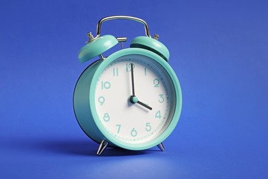 Photo of One turquoise alarm clock on blue background