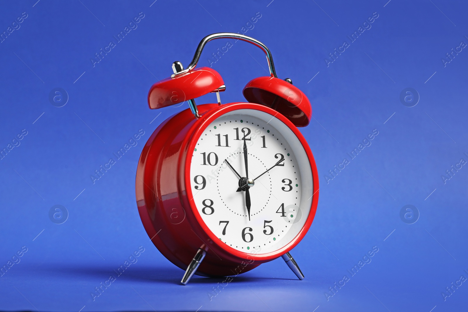 Photo of One red alarm clock on blue background