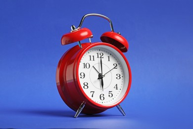 Photo of One red alarm clock on blue background