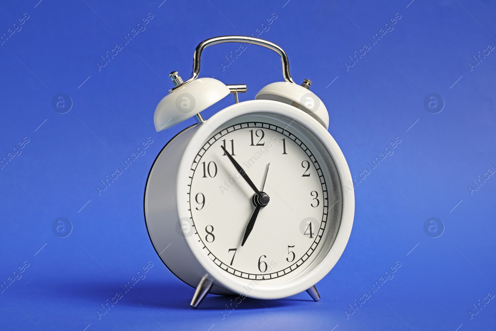 Photo of One white alarm clock on blue background