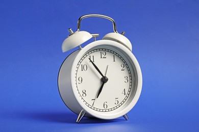 Photo of One white alarm clock on blue background