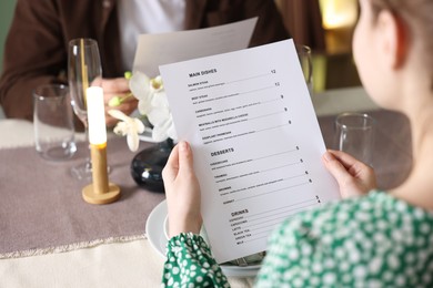 Photo of Couple choosing dishes from menu at table in restaurant, closeup