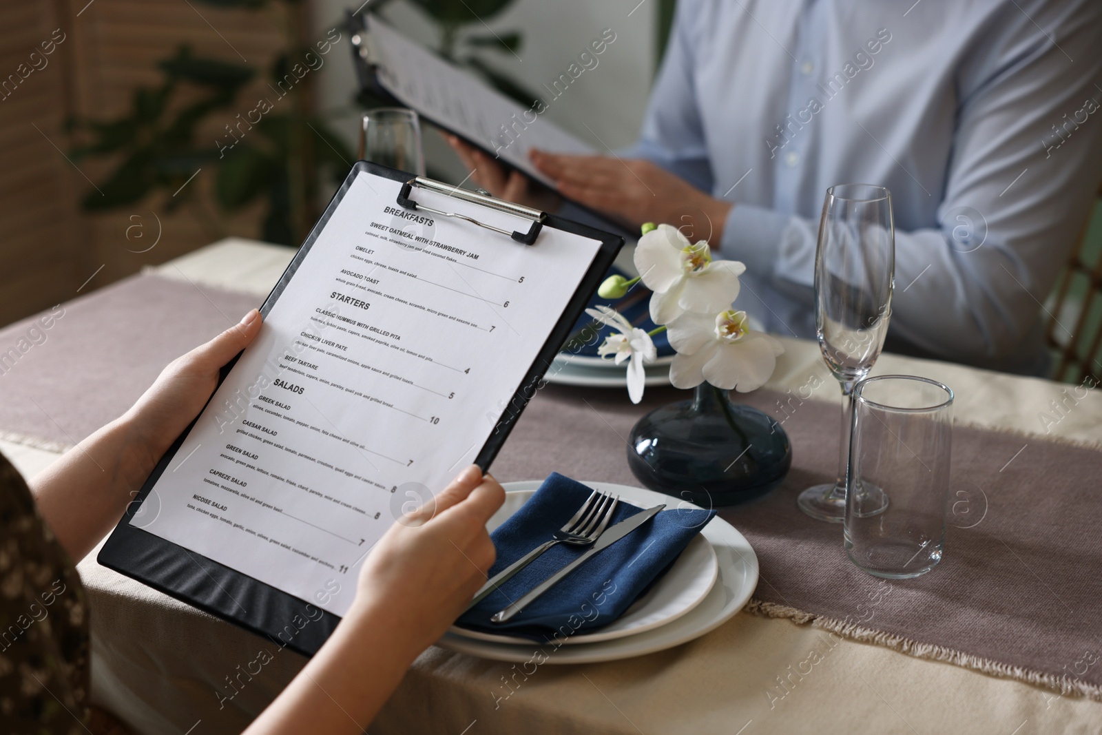 Photo of Couple choosing dishes from menu at table in restaurant, closeup