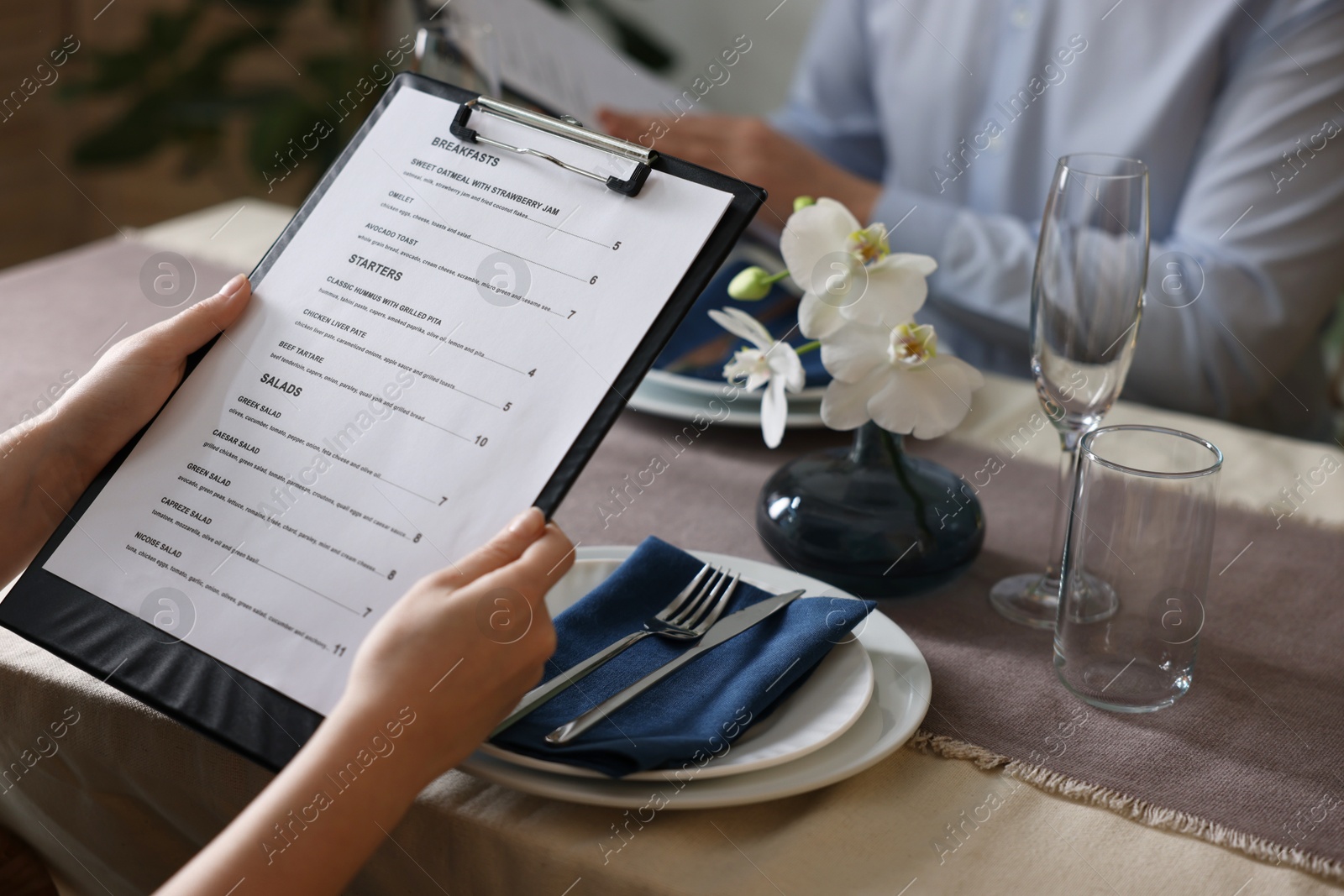 Photo of Couple choosing dishes from menu at table in restaurant, closeup