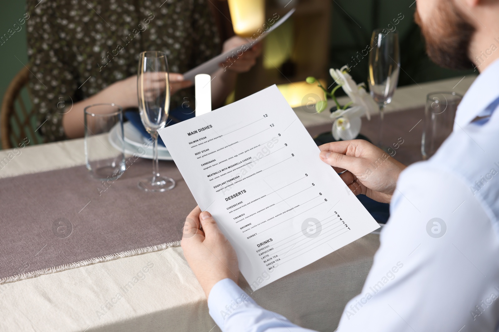 Photo of Couple choosing dishes from menu at table in restaurant, closeup