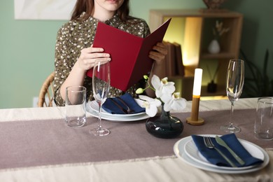 Photo of Woman choosing dish from menu at table in restaurant, closeup