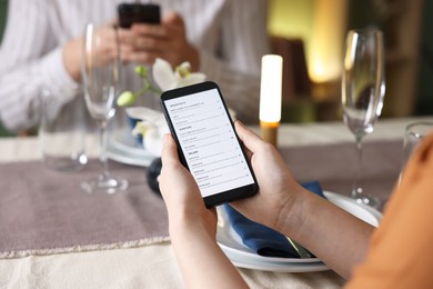 Photo of Couple choosing dishes from digital menu at restaurant, closeup