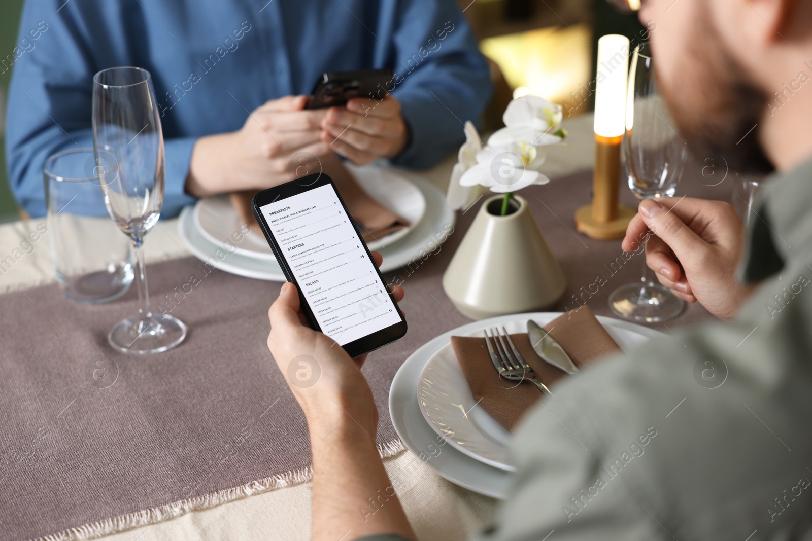 Photo of Couple choosing dishes from digital menu at restaurant, closeup