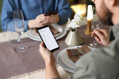 Photo of Couple choosing dishes from digital menu at restaurant, closeup