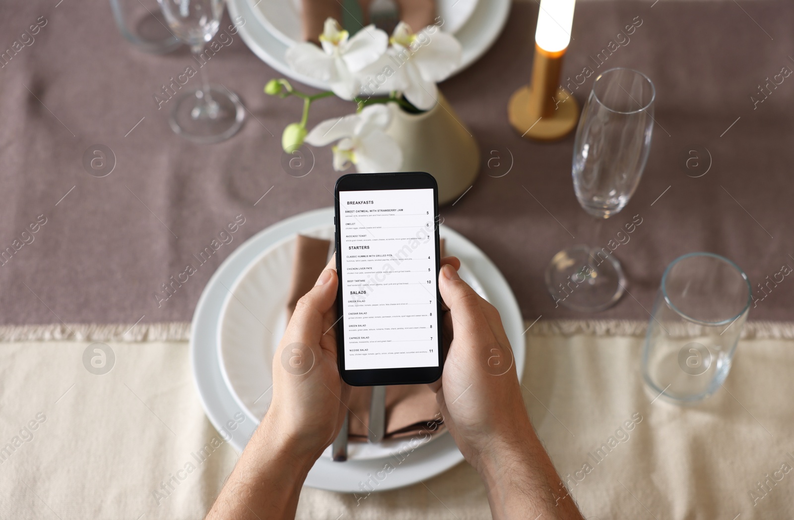 Photo of Man choosing dish from digital menu at table in restaurant, top view