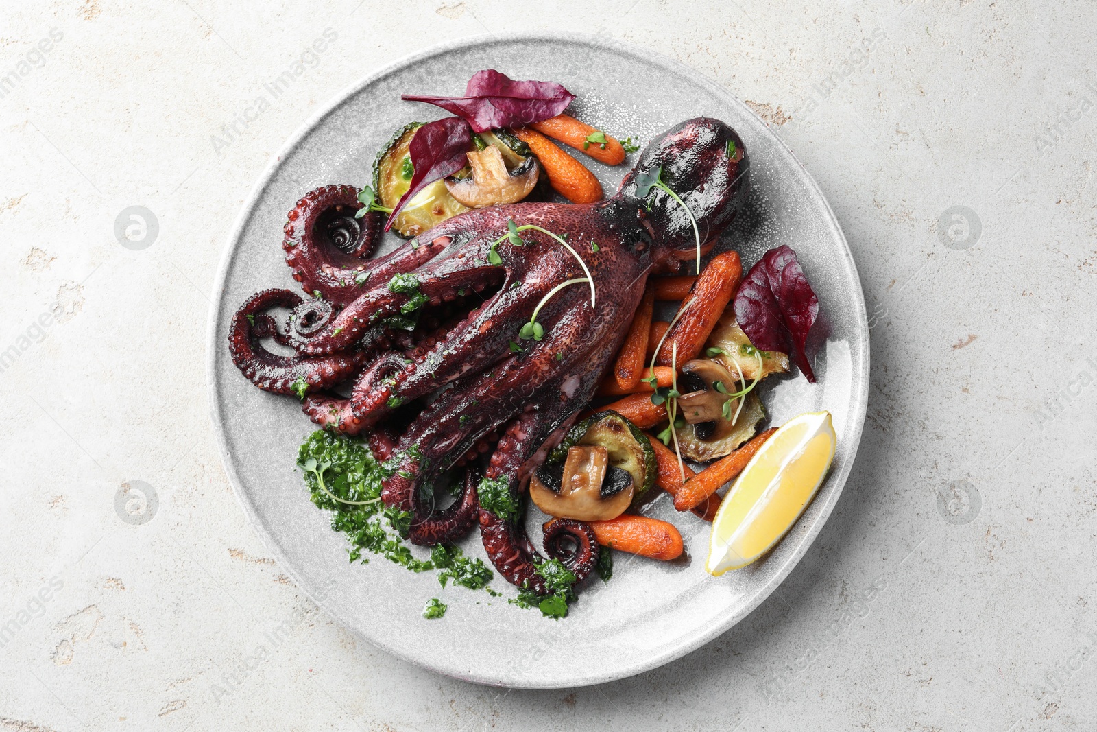 Photo of Roasted octopus with vegetables and mushrooms on light grey table, top view