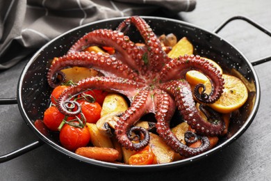 Photo of Fried octopus with lemon, mushroom and vegetables on grey table, closeup